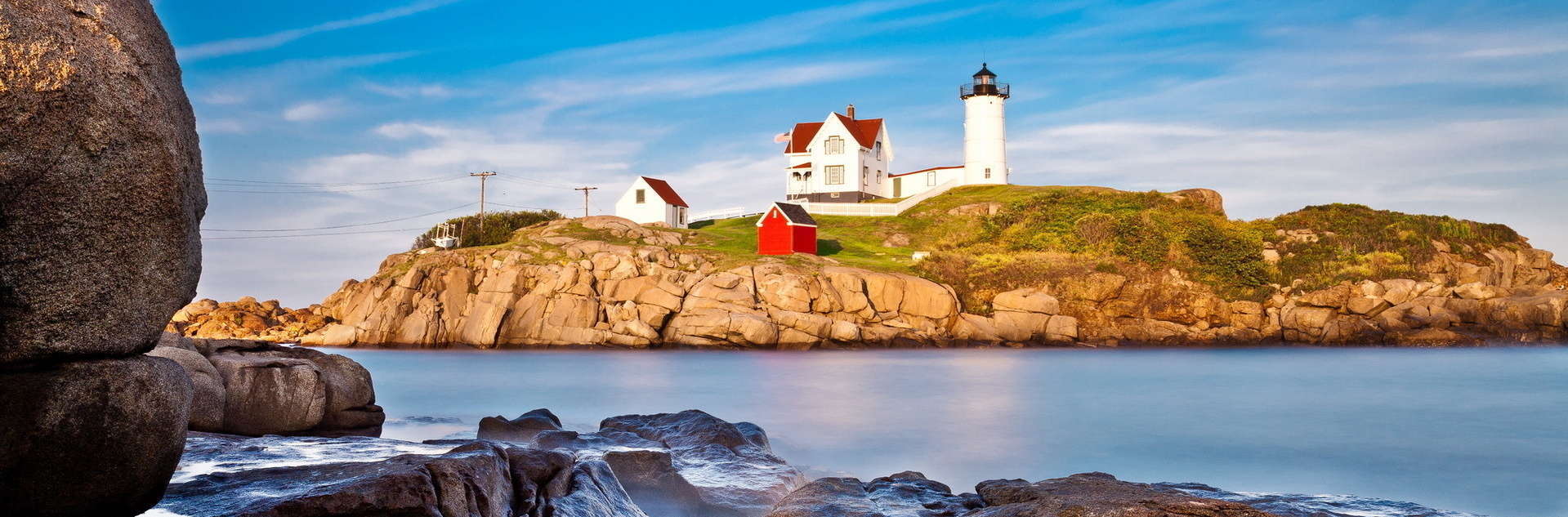 Historic lighthouse along rocky cliff in Maine.