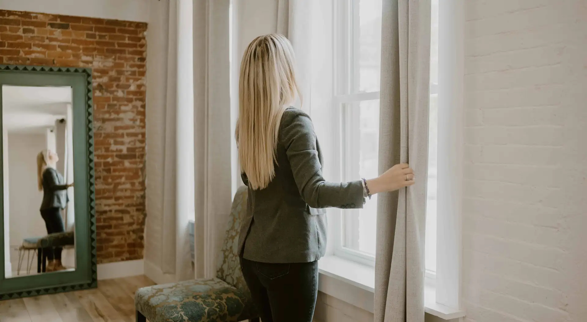 The girl opens the curtains.