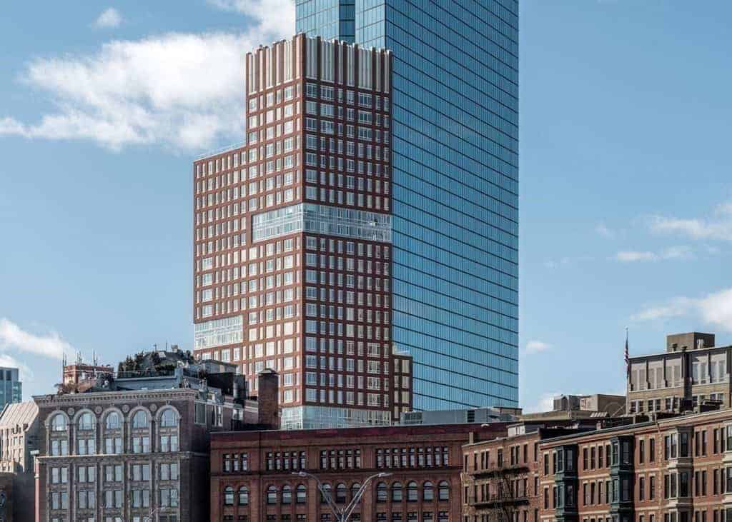 The Clarendon rising above Back Bay rooftops beside the John Hancock Tower