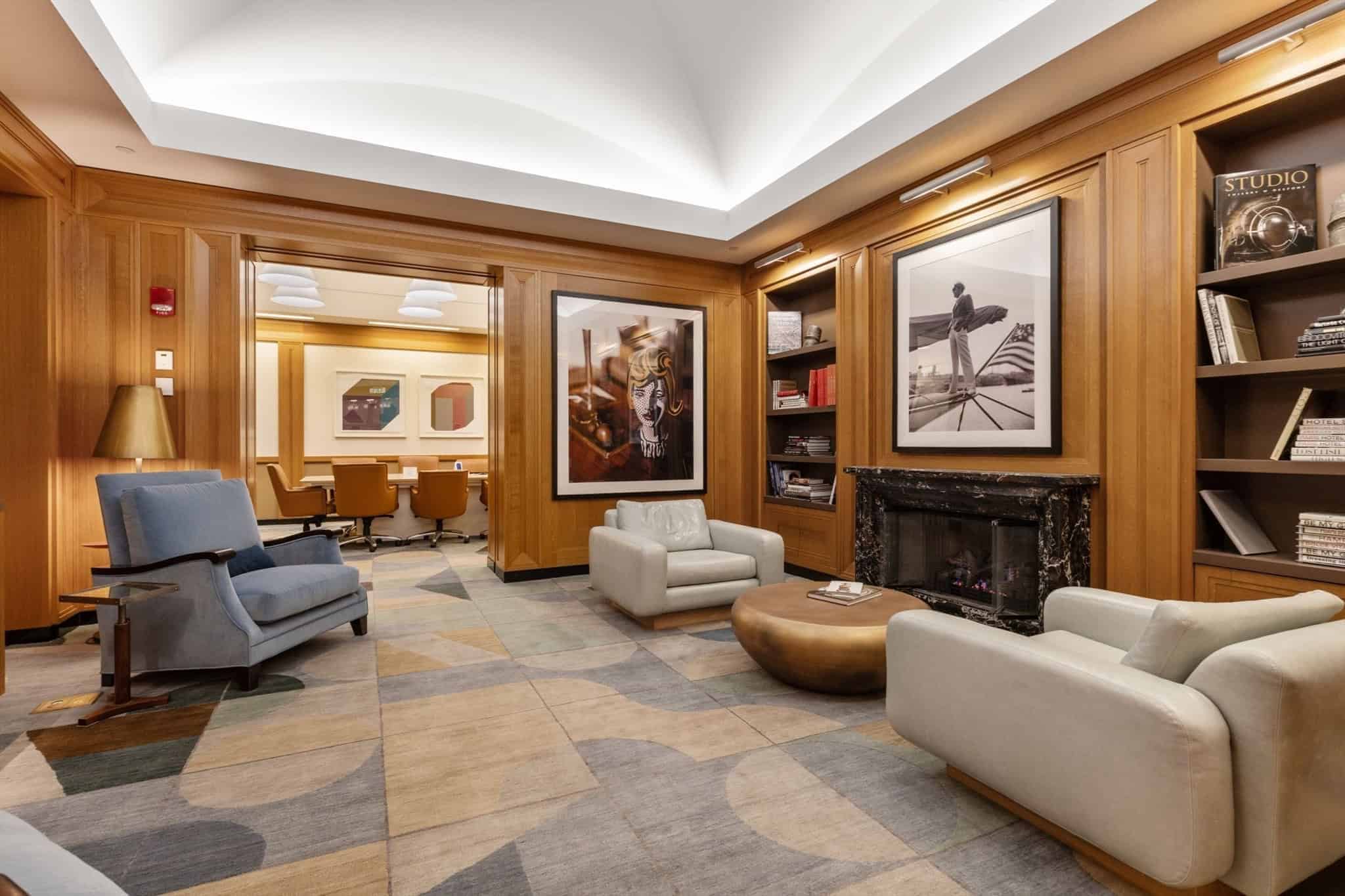 Wood-panelled resident library with fireplace and conference room beyond