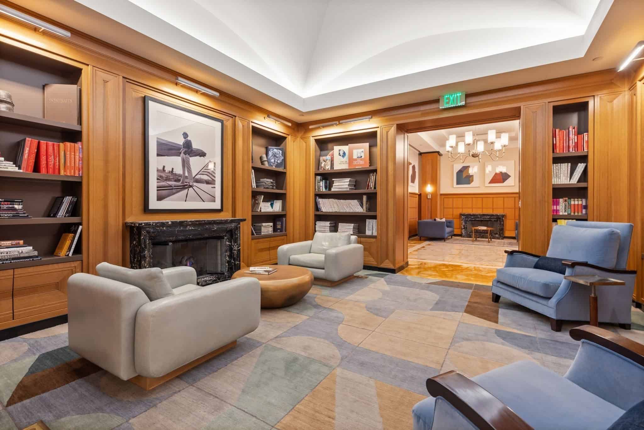 Resident library with bookshelves, marble fireplace and lounge seating