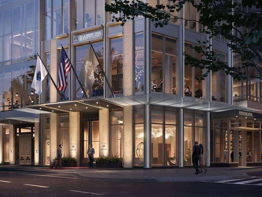 The illuminated Raffles Boston entrance with flags at night
