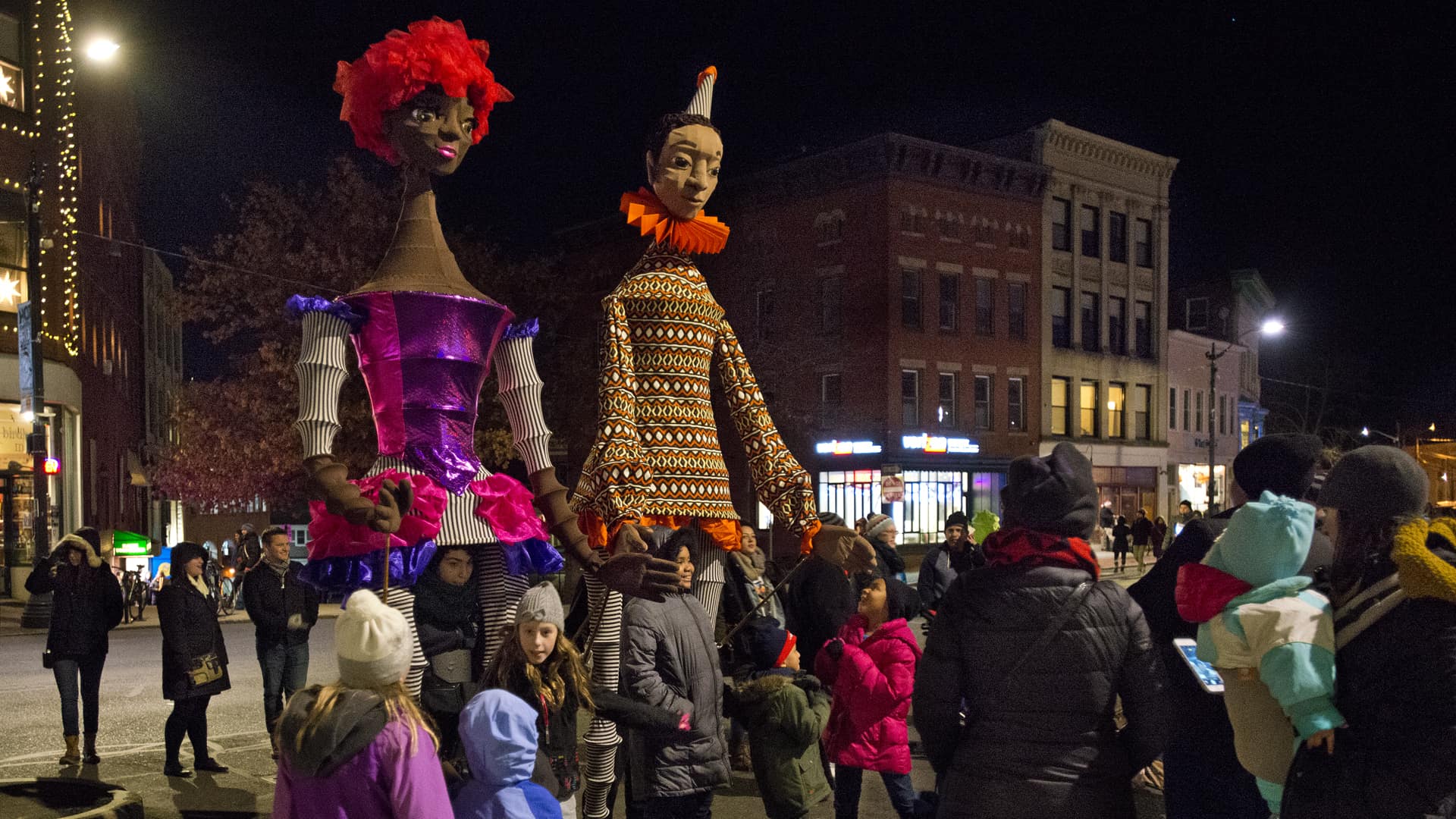 large puppets at parade downtown at night