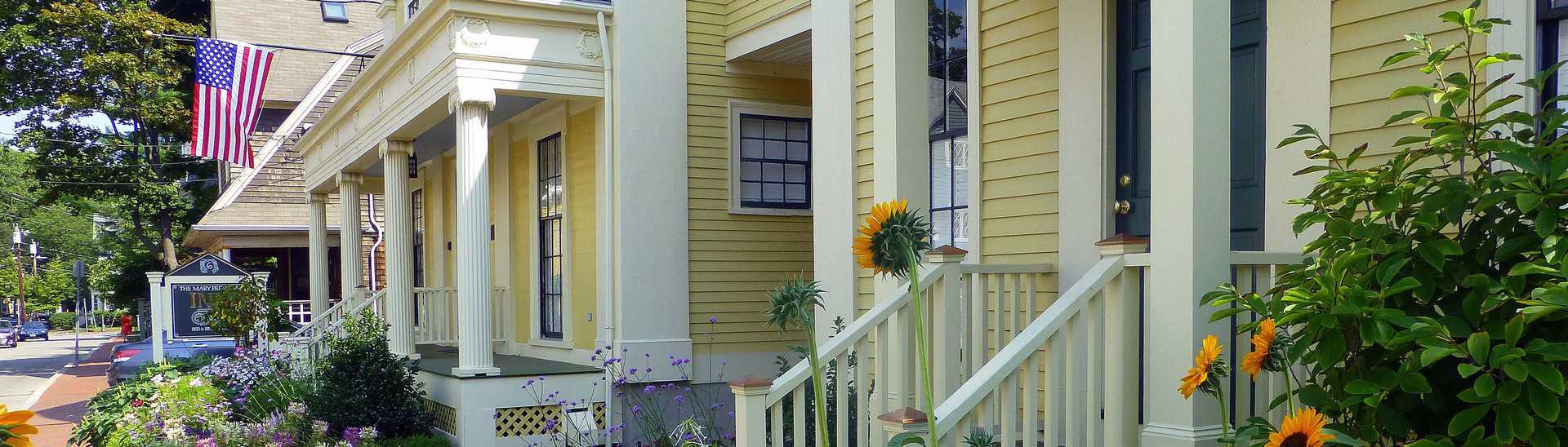 Exterior of yellow house along street with white pillars
