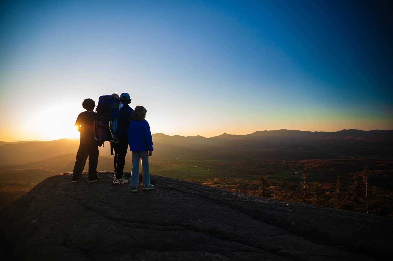 Family watching sunset on top of The Pinnacle, Stowe, Vermont, USA