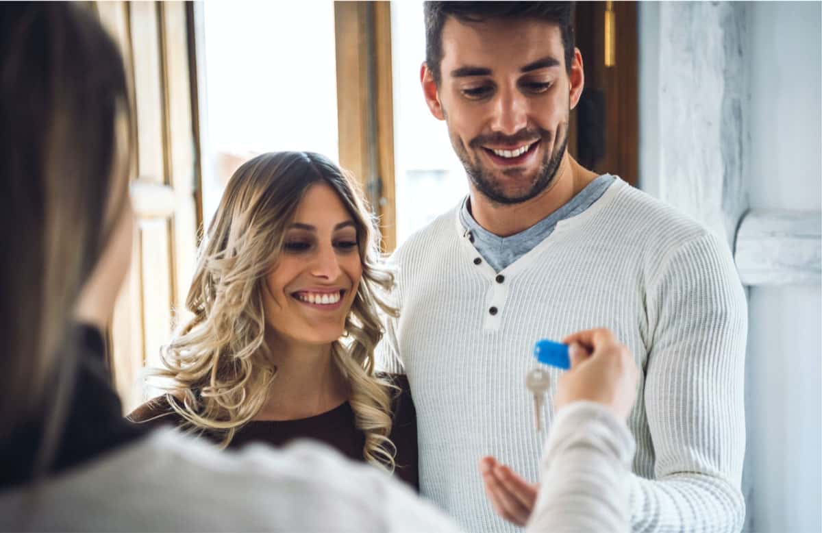 man and woman receiving keys after buying a home.